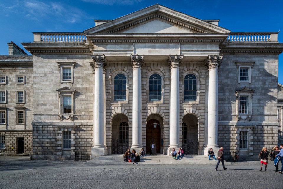 People sit on the stops of an 18th century building with 4 tall pillars at the entrance